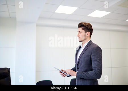 Junger Geschäftsmann Brünette mit Tablet-PC im Büro. Stockfoto