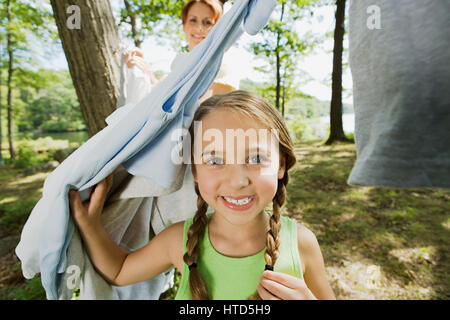 Mädchen und Mutter hängende Kleidung im Wald Stockfoto