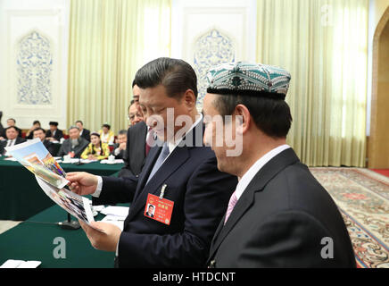 Peking, China. 10. März 2017. Chinesischen Staatspräsidenten Xi Jinping befasst sich mit Fotos der Familie von Kurban Tulum, wenn eine Podiumsdiskussion mit Abgeordneten Beitritt zum 12. nationalen Volksarmee Kongress (NPC) aus Xinjiang Uygur Autonome Region auf der jährlichen Tagung der NPC in Peking, Hauptstadt von China, 10. März 2017. XI wurde geschrieben, um eine Tochter von Kurban Tulum, die zweimal durch den verstorbenen Vorsitzenden Mao Zedong empfangen wurde, unterstreicht ethnische Solidarität und Bemühungen, eine glänzende Zukunft für Xinjiang unter der Führung der kommunistischen Partei von China (CPC) zu bauen. Bildnachweis: Xinhua/Alamy Live-Nachrichten Stockfoto