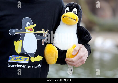 Ein Mann steht mit einem T-shirt und einem Stofftier das Linux-Maskottchen, der Pinguin Tux, bei einem Presse-Event im Tierpark in Limbach-Oberfrohna, Deutschland, 10. März 2017. Zwei der Pinguine wurden von den Organisatoren der Chemnitzer Linux-Tage-Veranstaltung am selben Tag angenommen. Als Maskottchen des freien Betriebssystems Mitte der 1990er Jahre wurde der Pinguin Tux von Linux-Gründer gewählt. Tausende von Gäste aus ganz Europa werden auf der kommenden 19. Chemnitzer Linux-Tage-Veranstaltung am 11. und 12. März 2017 erwartet. Im Mittelpunkt des diesjährigen Linux-Tage ist auf Zugänglichkeit und Benutzerfreundlichkeit. Foto: Jan W Stockfoto