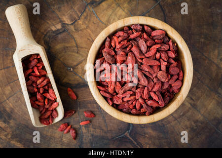 Getrocknete Goji-Beeren in einer Holzschale über hölzerne Hintergrund. Nahaufnahme, Draufsicht, horizontales Bild Stockfoto