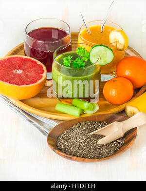 Grüne, gelbe und rote Smoothies, Säfte, Getränke, Getränke mit frischem Obst und Gemüse auf einem weißen Hintergrund aus Holz. Stockfoto