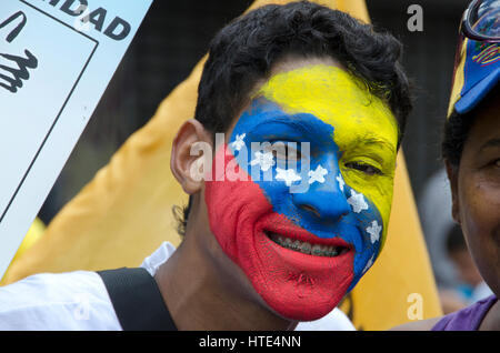 Ein junger Mann mit seinem Gesicht gemalt mit der Flagge Venezuelas, beteiligt sich an einer Demonstration gegen die Regierung von Venezuela Stockfoto