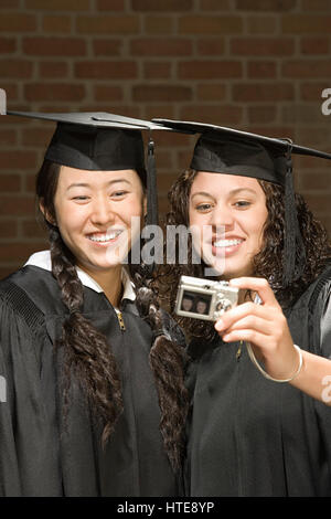 Zwei weibliche Absolventen mit dem Fotografieren Stockfoto