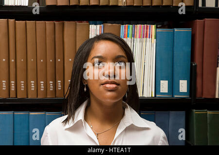 Studentin in der Bibliothek ein Buch zu wählen Stockfoto