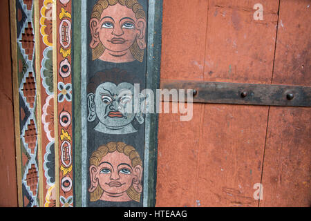 Bhutan Thimphu. Chong Gia ca Tempel. Detail der kunstvoll bemalten Gesichtern um hölzerne Tempeltür. Stockfoto