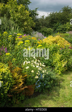 Bunte Blumenbeete im Garten Landhausstil. Gemischte Pflanzung von Sträuchern und Stauden in vollem Wachstum, Mitte Juli. Stockfoto