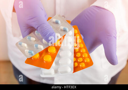 Arzt mit Pillen in Händen mit Handschuhen. Pillen Arzt Handschuhe reichen Sonnenlicht Hände weiße Konzept Stockfoto