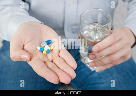 Person, die die verschiedenen Arten von Drogen. Pillen Palm mit Wasserglas Mann Medizin Gesundheitskonzept Stockfoto