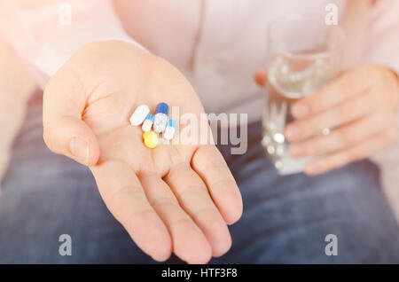 Person, die die verschiedenen Arten von Drogen. Pillen Palm mit Wasserglas Mann Medizin Gesundheitskonzept Stockfoto