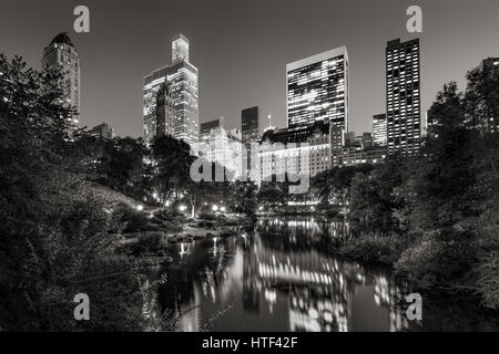 Midtown Manhattan Wolkenkratzer Abend beleuchtet. Die Gebäude des Central Park South spiegeln sich in den Teich. New York City. & Schwarz Stockfoto