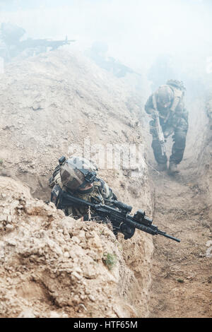 Kader von Elite französische Fallschirmjäger des 1. Marine Infanterie Parachute Regiment RPIMA in Aktion in feindlichen Schützengräben mit Schießpulver Rauch gefüllt Stockfoto