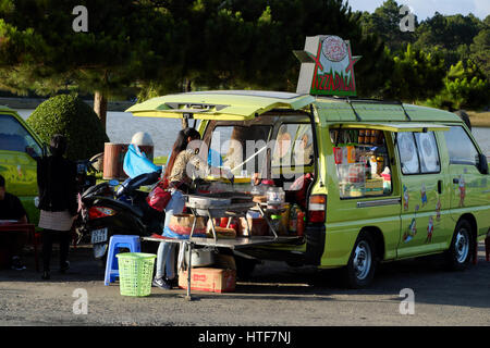 DA LAT, VIET NAM - DEC 27, 2016: Vietnamesische Händler verkauft Speiselokal mit Store vom Auto in der Nähe von Xuan Huong See an Frühlingstag an Dalat, Vietnam Stockfoto