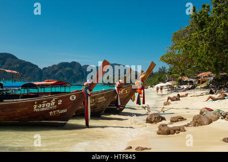 Drei traditionelle hölzerne Boote vertäut an einem sonnigen Traumstrand in Thailand Stockfoto