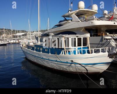 Alten Mittelmeer Caique Boot angedockt neben modernen luxuriösen Motoryachten im Hafen von Cannes, Frankreich. Stockfoto