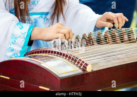 Eine Mädchen spielt Guzheng.The Guzheng oder gu Zheng, auch einfach als Zheng, ist eine chinesische Zither gezupft. Es hat 18 oder mehr Saiten und bewegliche Brücke Stockfoto