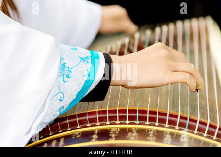 Eine Mädchen spielt Guzheng.The Guzheng oder gu Zheng, auch einfach als Zheng, ist eine chinesische Zither gezupft. Es hat 18 oder mehr Saiten und bewegliche Brücke Stockfoto