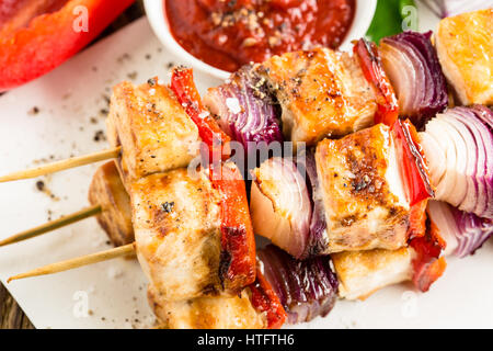 Gegrillte Hähnchen-Spieße mit Gemüse auf Holztisch Stockfoto