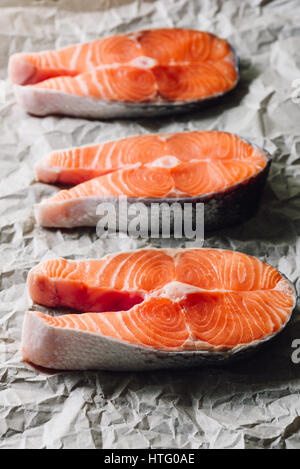 Drei rohen Lachs Steaks auf Pergamentpapier. Vertikale. Stockfoto