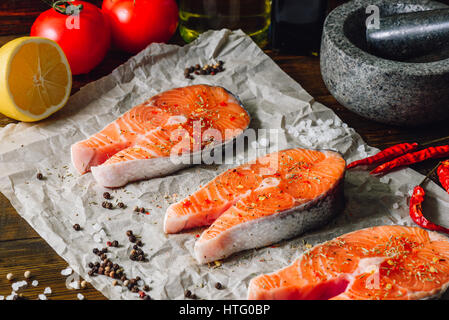 Roher roter Fisch und einigen Gewürzen auf Pergamentpapier Stockfoto