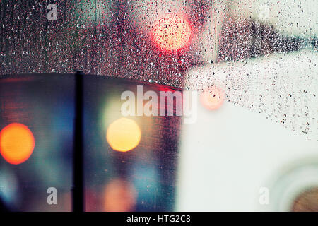 Bokeh Licht und Regen fällt auf einen Bus-Fenster. Stockfoto