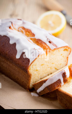 Hausgemachte glasierten Zitronen Sandkuchen auf rustikalen Holztisch, in Scheiben geschnitten und fertig zum Verzehr Stockfoto