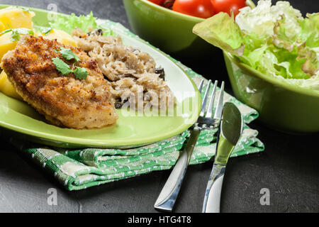 Gebratenes Schweinefleisch Schnitzel serviert mit gekochten Kartoffeln und gebratene Sauerkraut auf einem Teller Stockfoto