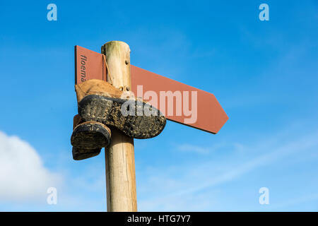 Schild am Wegesrand Rota Vicentina Ferngespräche in der Algarve in Portugal, mit Wanderschuhen zum Trocknen gehängt. Stockfoto