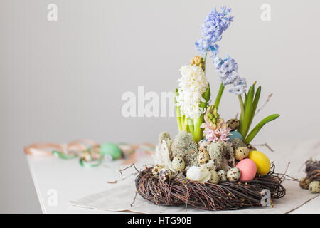 Glücklich Osterkarte mit bunten Blumen, Federn und Wachteln Eiern auf weißem Hintergrund. Schönen Frühling Komposition Stockfoto