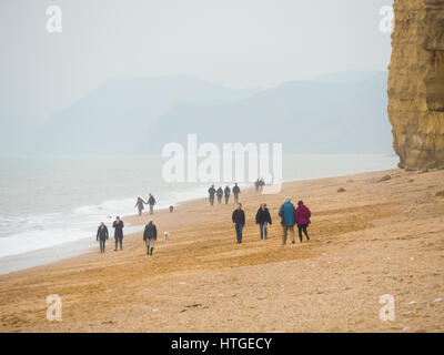 Burton Bradstock, Dorset, UK, 11. März 2017, Menschen am Strand Burton Bradstock Strand spazieren an einem dunstigen und nebligen Tag im West Dorset St Burton Bradstock Strand, Dorset, UK. © Dan Tucker/Alamy Live-Nachrichten Stockfoto