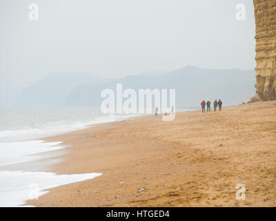 Burton Bradstock, Dorset, UK, 11. März 2017, Menschen am Strand Burton Bradstock Strand spazieren an einem dunstigen und nebligen Tag im West Dorset St Burton Bradstock Strand, Dorset, UK. © Dan Tucker/Alamy Live-Nachrichten Stockfoto