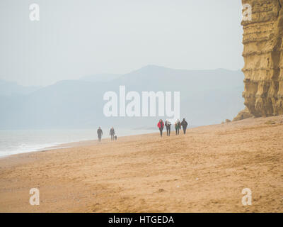 Burton Bradstock, Dorset, UK, 11. März 2017, Menschen am Strand Burton Bradstock Strand spazieren an einem dunstigen und nebligen Tag im West Dorset St Burton Bradstock Strand, Dorset, UK. © Dan Tucker/Alamy Live-Nachrichten Stockfoto