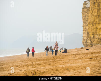 Burton Bradstock, Dorset, UK, 11. März 2017, Menschen am Strand Burton Bradstock Strand spazieren an einem dunstigen und nebligen Tag im West Dorset St Burton Bradstock Strand, Dorset, UK. © Dan Tucker/Alamy Live-Nachrichten Stockfoto