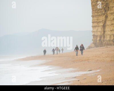 Burton Bradstock, Dorset, UK, 11. März 2017, Menschen am Strand Burton Bradstock Strand spazieren an einem dunstigen und nebligen Tag im West Dorset St Burton Bradstock Strand, Dorset, UK. © Dan Tucker/Alamy Live-Nachrichten Stockfoto