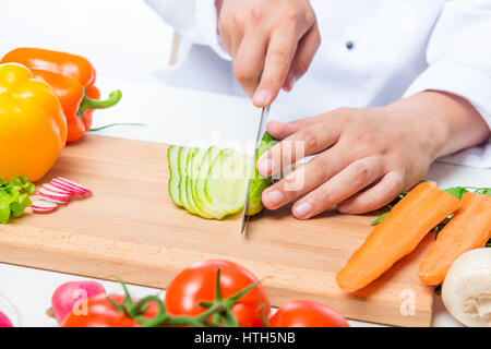 Koch schneidet die Gurkensalat sorgfältig auf ein Holzbrett Stockfoto
