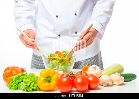 Hände-Chef unter Rühren mit einem Holzlöffel Gemüsesalat in einer Schüssel auf dem Tisch Stockfoto
