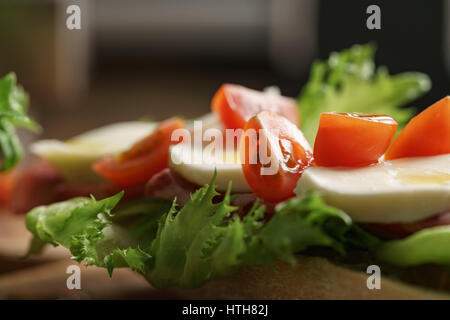 Open-Sandwich mit Schinken, Mozzarella und Tomaten auf Küchentisch, flachen Fokus Stockfoto