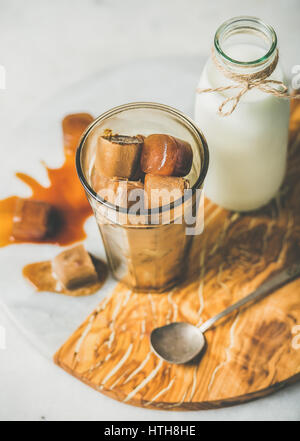 Glas mit gefrorenen Kaffee Eiswürfel und Milch an Bord Stockfoto