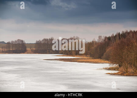 Zeitigen Frühjahr. Schlamm-Saison. See unter Eis und Schnee schmelzen. Bewölkten Frühlingstag. Ländliches Motiv Frühling. Stockfoto