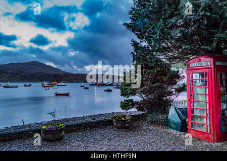 Telefonzelle mit Blick auf Ben Tianavaig und der Pier am Hafen von Portree, Isle Of Skye, Schottland Stockfoto