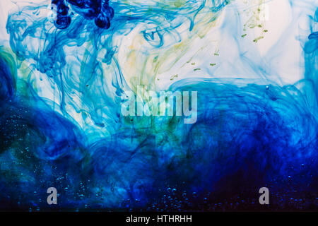 Wolken aus blauen und gelben Tinte auflösen in Wasser Stockfoto
