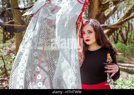 mysteriöse Frau Hexe im Wald mit einer Kerze, versteckt hinter den Kulissen Stockfoto