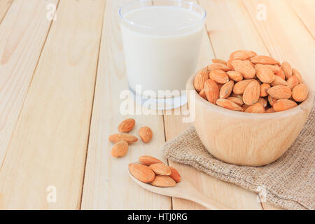 Mandelmilch aus Glas mit Mandeln auf Holztisch, Draufsicht mit textfreiraum und Text. Stockfoto