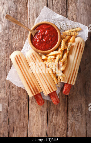 Gegrillte Hot-Dog Brötchen mit Pommes Frites und Tomaten Sauce close-up auf dem Tisch. Vertikale Ansicht von oben Stockfoto