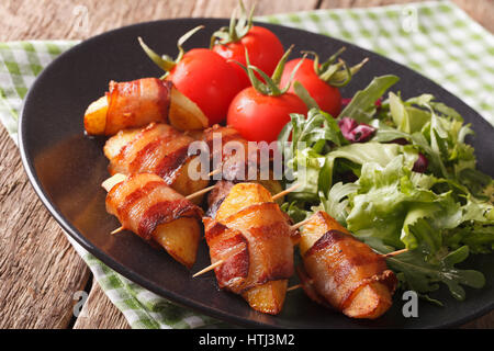Bratkartoffeln, eingewickelt in Speck und frischem Salat Nahaufnahme auf einer Platte. horizontale Stockfoto