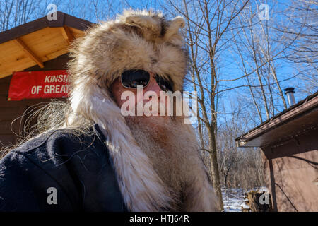 Bärtiger Mann, grauen Bart, graue Haare, mittlerer gealterter Mann tragen Kojote (Canis Latrans) Pelz / Fell Hut, rau auf der Suche, in London, Ontario, Kanada. Stockfoto