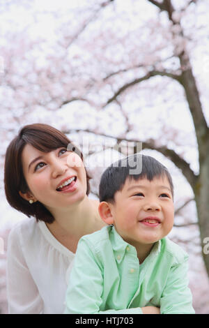 Japanische Mutter und Sohn mit Kirschblüten in einem Stadtpark Stockfoto