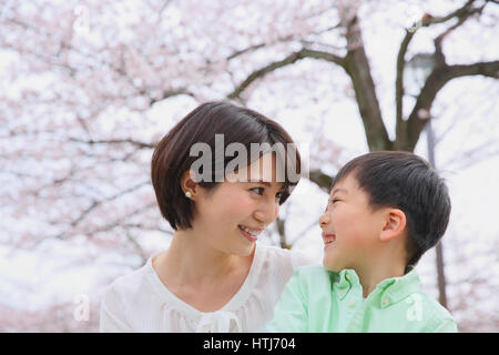 Japanische Mutter und Sohn mit Kirschblüten in einem Stadtpark Stockfoto