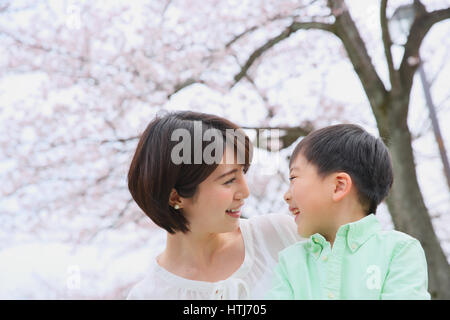 Japanische Mutter und Sohn mit Kirschblüten in einem Stadtpark Stockfoto