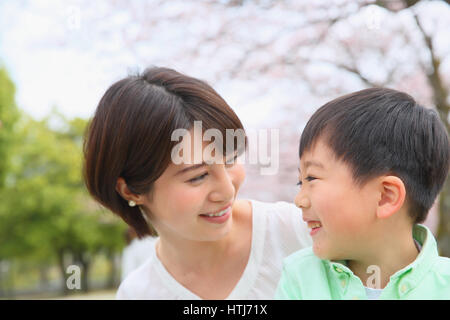 Japanische Mutter und Sohn mit Kirschblüten in einem Stadtpark Stockfoto